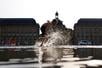 A child plays in the shallow water of the Miroir d’eau to cool off as a heatwave hits France, in Bordeaux, France, August 12, 2025. REUTERS/Abdul Saboor
