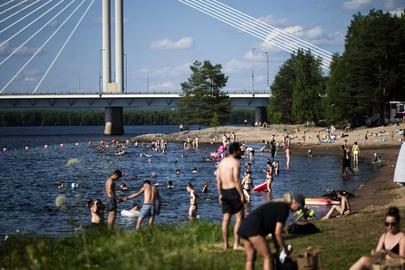 Picture taken on July 23, 2025 shows people bathing at the Ounaskoski Beach at the Arctic Circle in Rovaniemi, Finnish Lapland. Finland has broken an over 50-year-old weather record as the country is witnessing the longest period of temperatures above 30 degrees Celsius, the Finnish Meteorological Institute said. (Photo by Jouni Porsanger / Lehtikuva / AFP) / Finland OUT