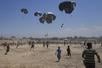 Palestinians rush to collect humanitarian aid airdropped by parachutes into Zawaida in the central Gaza Strip, Monday, Aug. 4, 2025. (AP Photo/Abdel Kareem Hana)