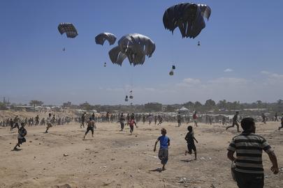 Palestinians rush to collect humanitarian aid airdropped by parachutes into Zawaida in the central Gaza Strip, Monday, Aug. 4, 2025. (AP Photo/Abdel Kareem Hana)