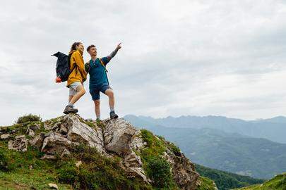 Two hikers standing on a mountain top, pointing at the scenic view