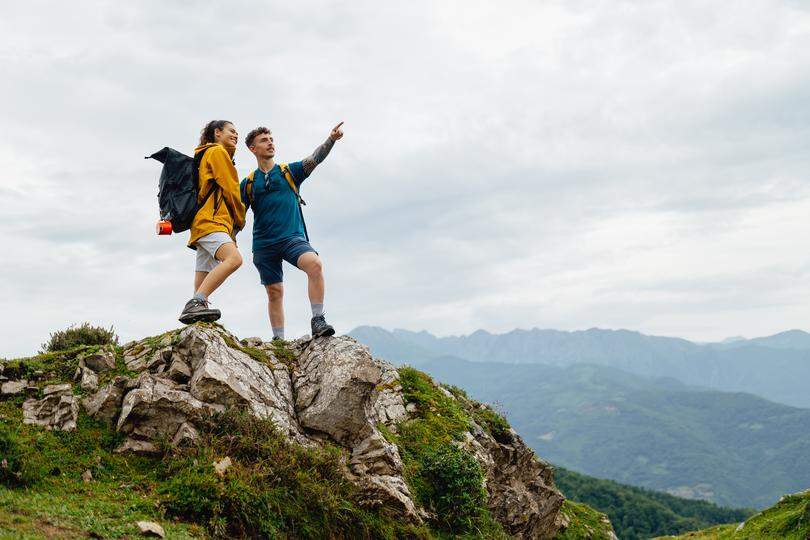 Two hikers standing on a mountain top, pointing at the scenic view
