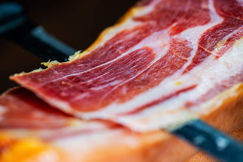 Chef cutting dry-cured spanish ham Jamon.
